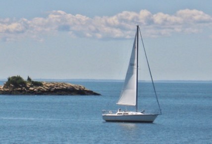 A white sail boat against a field of blue water and sky